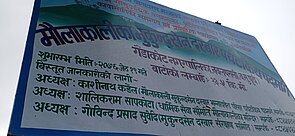 Close-up of a signboard with details of the hiking trail project at Mukundapur.